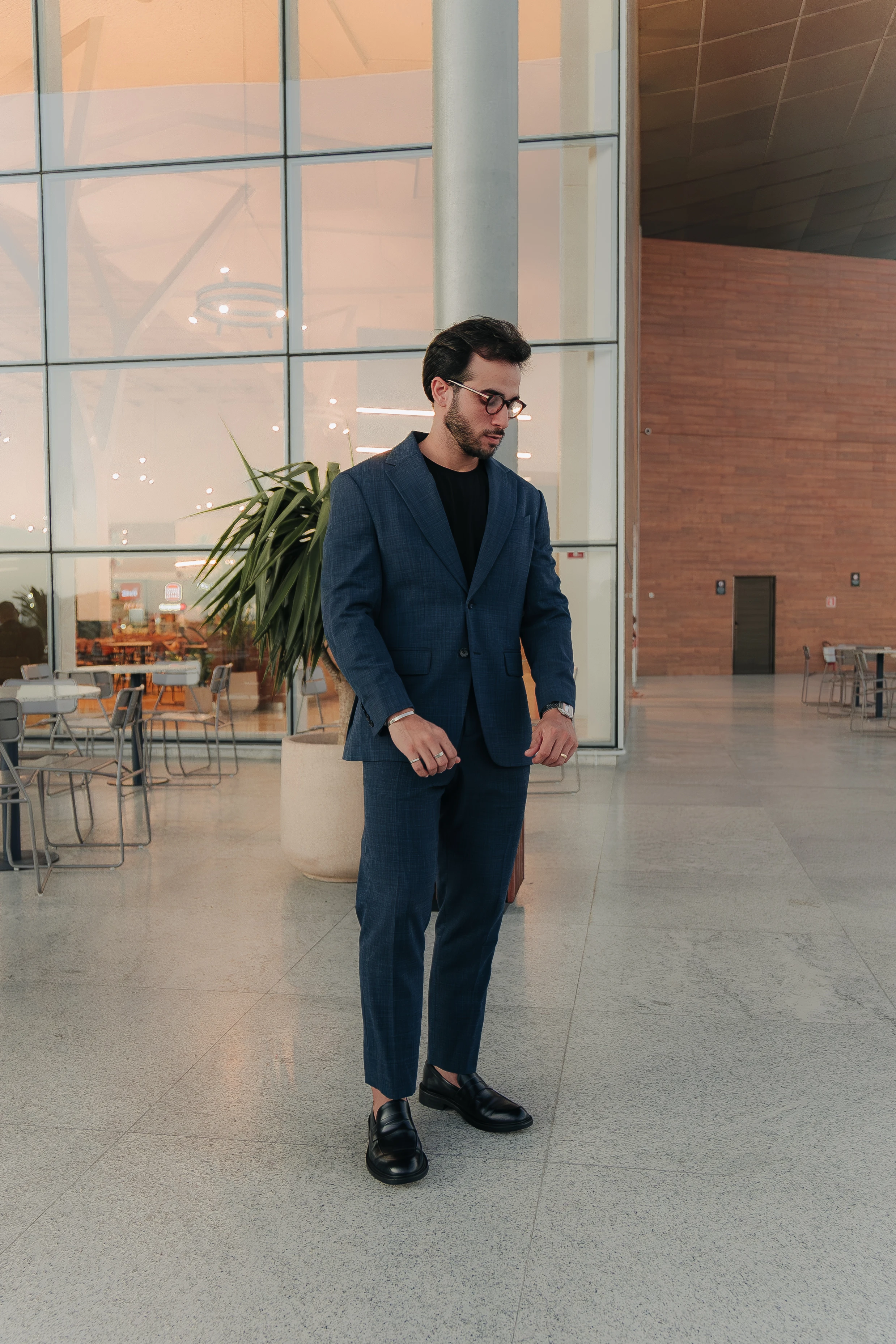 Jader Atila usando terno azul em um ambiente contemporâneo